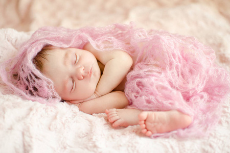 婴儿熟睡的女孩裹在针织材料, 躺在柔软蓬松的地毯上