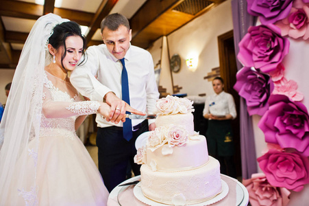 婚礼情侣在餐厅切他们华丽的白色婚礼蛋糕