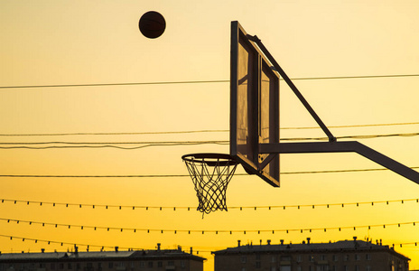 快速飞入在日落时球飞入篮球网照片