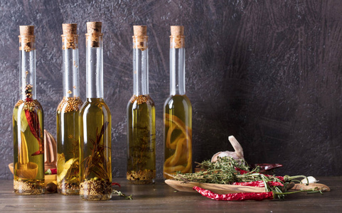 一张旧木桌上的一瓶橄榄油。橄榄油用不同的香料和草药。复制空间