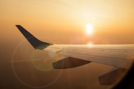 在黄色黎明或日落背景下的飞机机翼.飞机机翼从窗口照片