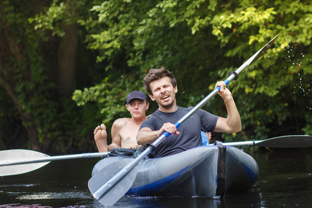 划船赛艇在夏天在河和划船桨。运动的人正在河里漂流。休闲。皮划艇运动员集团。年轻男子在船上的运动情绪与桨。在独木舟上游泳的人在水上