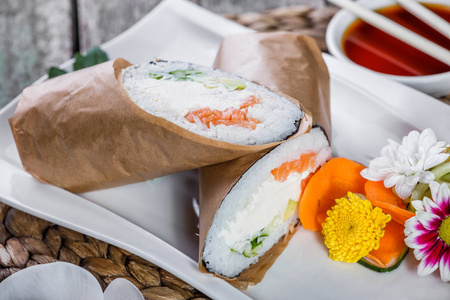 寿司卷有鲑鱼, 奶油芝士, 鳄梨和黄瓜在盘子里。日本料理健康的海洋食品