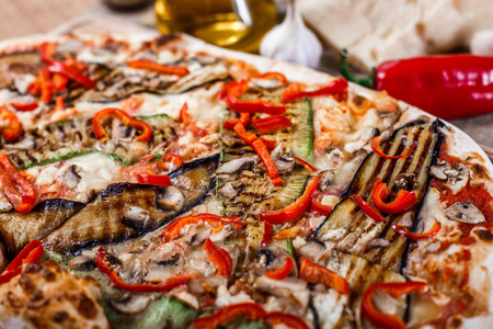 美味的比萨饼与鸡肉, 西葫芦, 茄子, 胡椒, 奶酪和蘑菇在木制的乡间餐桌上。顶部视图。色调