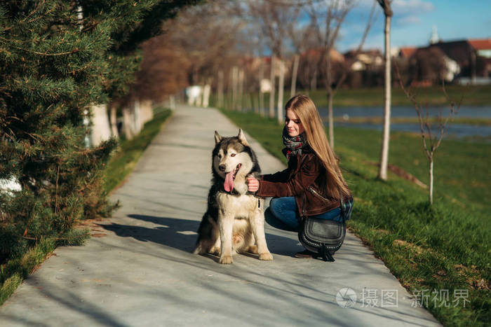一个女孩在遛狗沿堤防.美丽的赫斯基狗.这条河.春天