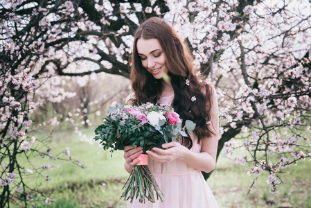 开花的树木的女人。婚礼花束在手里的女人