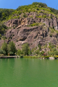 在岸边的绿色水柱与高岩石悬崖。悬崖的顶端是一棵翡翠草