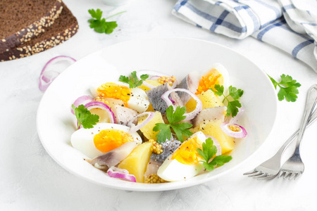 土豆沙拉配鲱鱼, 鸡蛋, 洋葱, 白盘子里有芥末的美味小吃