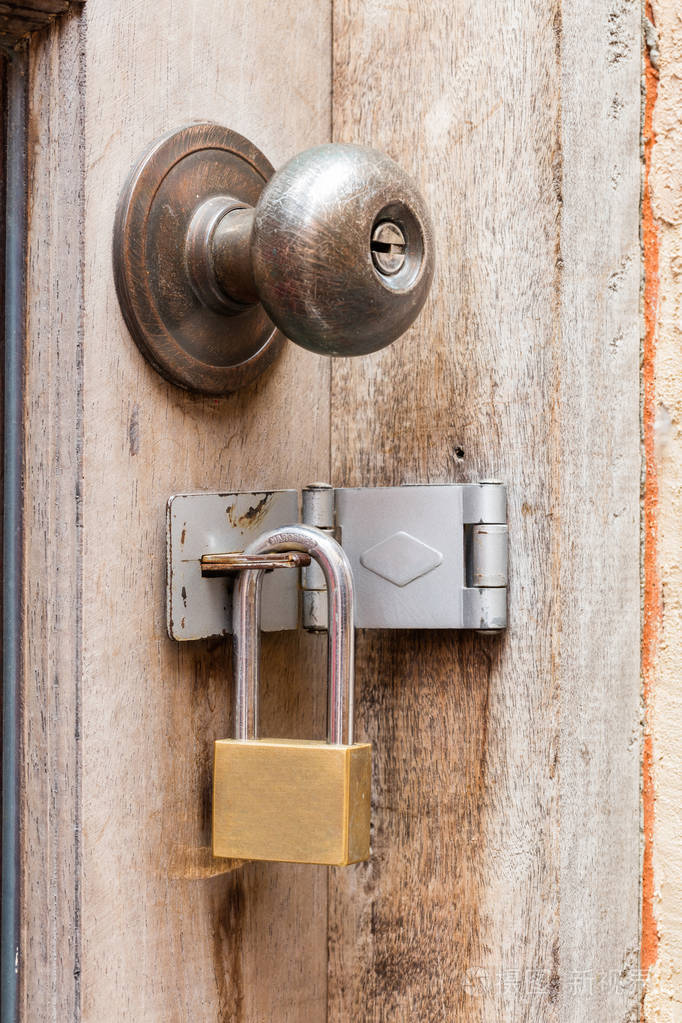 关闭生锈的老门旋钮和木门挂锁