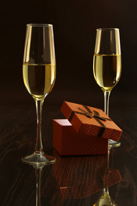 着白色的酒和礼物盒子，镜子桌子上的两个玻璃杯。名人组成。此处输入文字
