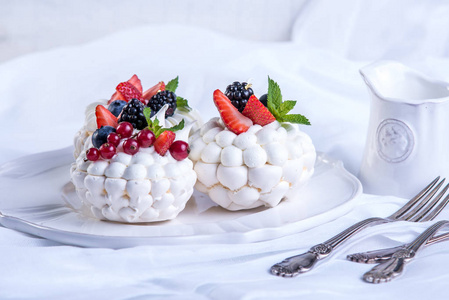 精致的白色蛋白甜饼与新鲜的浆果在盘子里。甜点帕夫洛娃白色背景。喜庆的婚礼蛋糕