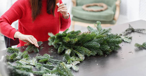 从松树树枝上的圣诞花环制造商度假。制作装饰装饰品的大师班。圣诞装饰用自己的手。新年庆典。花卉店