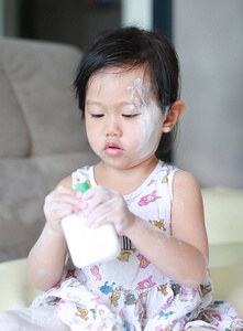 可爱的小婴儿的女孩，她的脸上和手上应用婴儿爽身粉