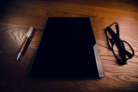手机 平板电脑 笔记本电脑用眼镜和钢笔。天然的木桌。办公室的背景。技术概念