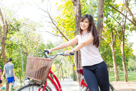 微笑健康亚洲妇女与自行车在公园