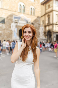 迷人的红发女子穿着白色礼服摆在佛罗伦萨街头