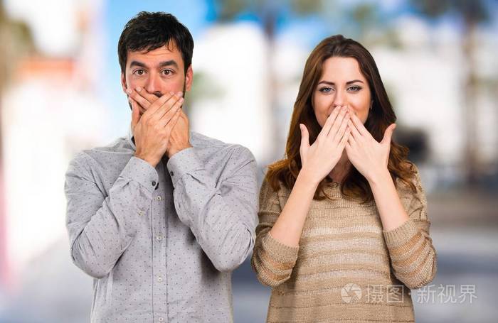 年轻夫妇捂着嘴在不专心的背景下