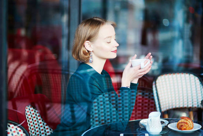 法国巴黎传统咖啡馆里喝咖啡的年轻优雅的女人