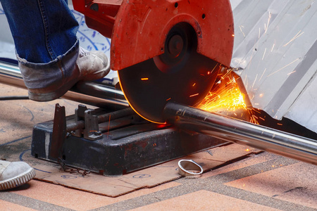 男工人用劈锯在施工工地切割厚不锈钢管