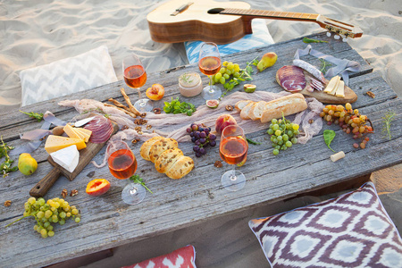 在日落时在波西米亚风格 食物和饮料浓到海滩野餐