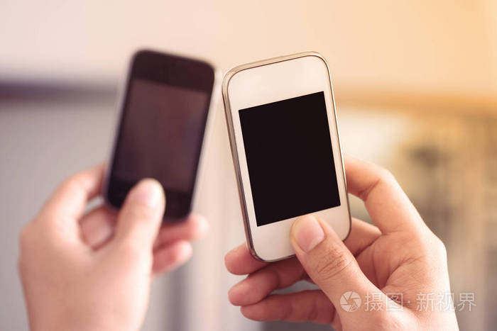 手拿着两个智能手机共享和链接数据照片-正版商用图片0q65q3-摄图新