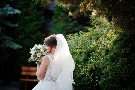 一个新娘的肖像独自走在她手中的花束在公园的婚礼日