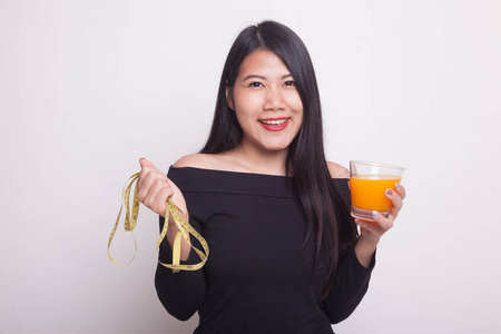 卷尺，白色背景上的年轻亚洲女人喝橙汁举行