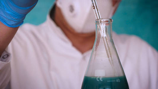 炼金术士 生物学家 采取各种物质的dna 在呼吸器 在保护帽 在护目镜 在白色的医疗礼服 烧瓶 绿色背景 科照片 正版商用图片0q6izn 摄图新视界