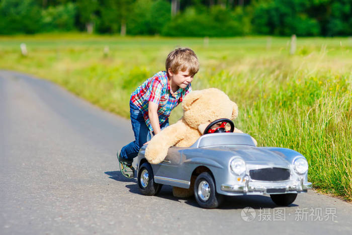 开车的大玩具和一只熊,在户外的小小孩男孩