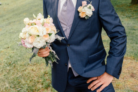 穿着西装的新郎手捧着一束华丽的结婚花束, 新婚夫妇。婚礼理念, 新娘花束