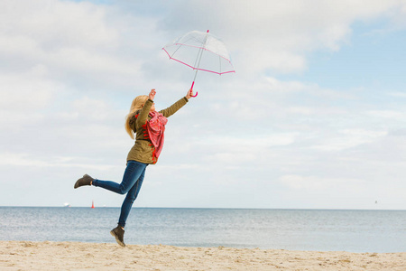 在海滩上跳跃着透明雨伞的女人图片