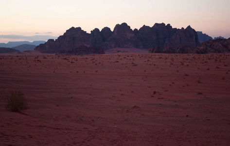 约旦 日落在洛矶山脉在瓦迪鲁姆沙漠，被称为月亮，一个著名的山谷，把切成的砂岩和花岗岩的岩石，看上去就像地球上的火星谷