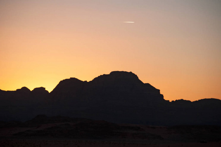 乔丹 在瓦迪鲁姆的一座山的黑色轮廓上炽热的日落沙漠，切成砂岩 花岗岩岩石，看上去就像地球上的火星月亮谷