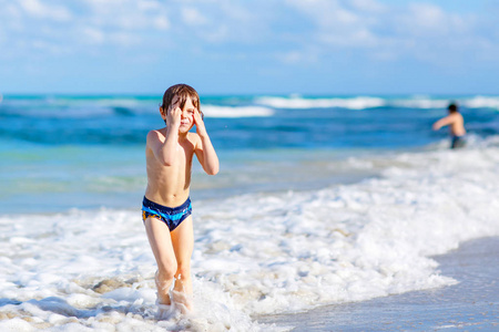 在佛罗里达州的海滩上玩的小金发孩子男孩