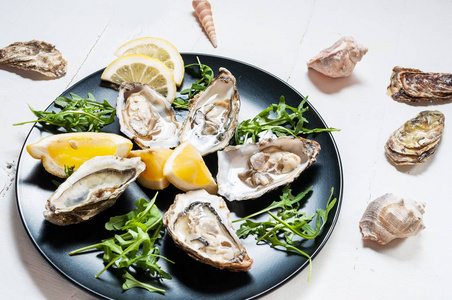 在白色的木桌上的黑版上的柠檬水果生蚝照片