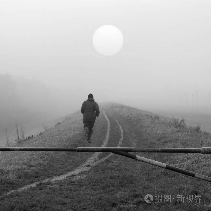 慢跑在性质上冷雾在黑色和白色的秋日的年轻人