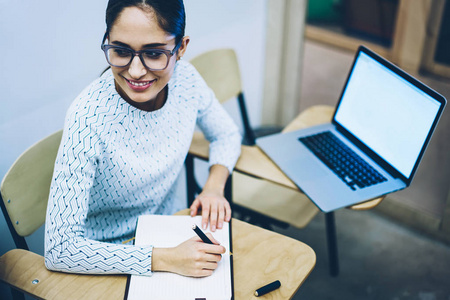 微笑的年轻妇女在设计学校的课程中学习信息坐在办公桌上的笔记本电脑