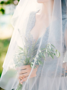 在 pal 的面纱下新娘手中的薰衣草婚礼花束