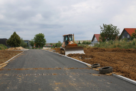 在德国修建了一条公路, 为建造一个新的住宅区铺设了公用线路. 推土机为房屋的建造准备土壤。