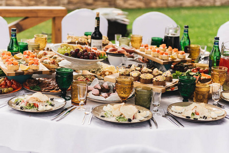 节日丰富的圆桌, 配有白色桌布和椅子, 配有各种美味的菜肴原创小吃和饮料。自助餐在自然
