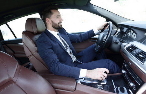 查看从侧面自信的商人坐在一辆车的车轮照片