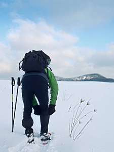旅游检查雪鞋。与冬季夹克和大背包徒步旅行者在雪中散步