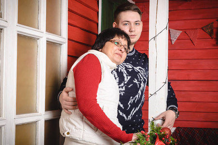 母亲和成人儿子近红色墙壁装饰的房子圣诞节和新年