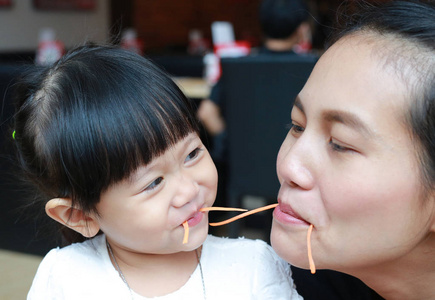 有趣的孩子女孩吃胡萝卜与母亲