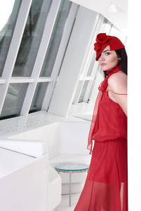 漂亮的年轻时髦的女人摆着红色的礼服和红色的帽子。时尚风格。带 instagram 样式滤镜的照片