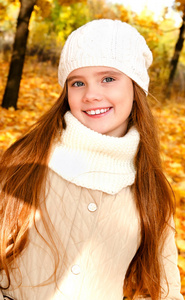在户外帽子可爱的微笑的小女孩的秋天画像