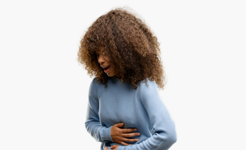 非洲裔美国妇女穿着一件毛衣, 手放在肚子上, 因为恶心, 痛苦的疾病感到不适。疼痛概念