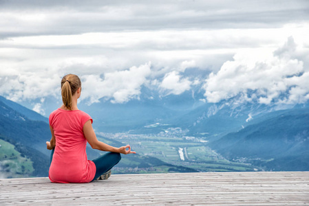 年轻女子打坐在山顶照片