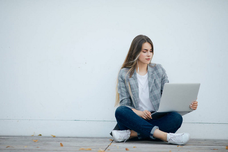 漂亮女孩坐在她的笔记本电脑和研究。白色背景
