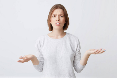 两个手掌在 longsleeve 的困惑不安的年轻女子的肖像看起来迷惑不解
